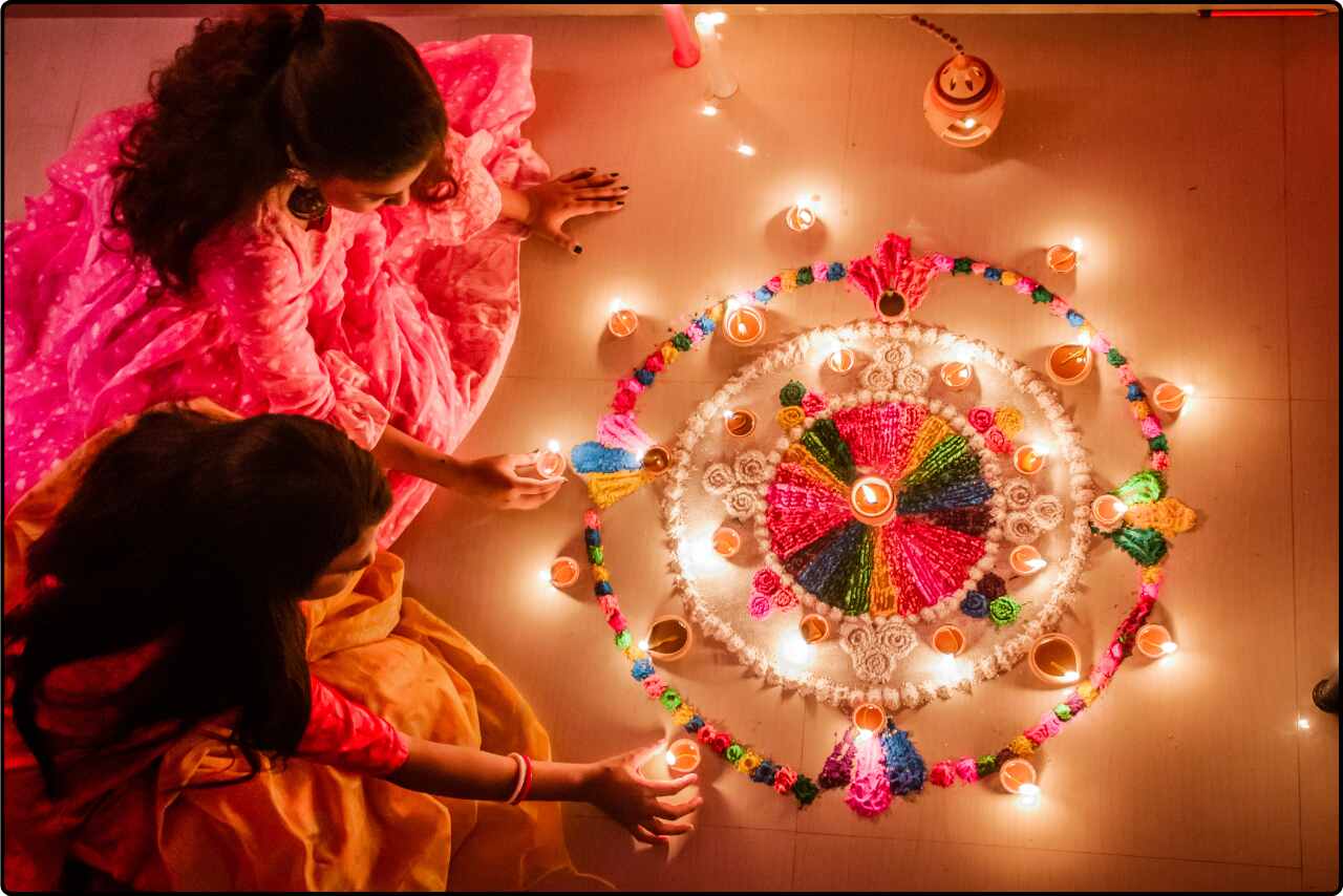 Diwali festival scene with women holding candles and colorful floral decorations.